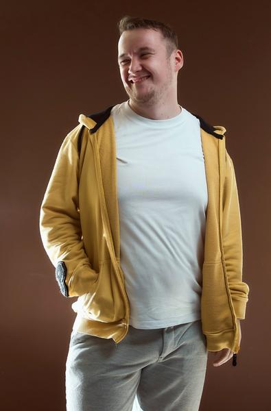 Portrait of the artist, wearing a yellow hoodie